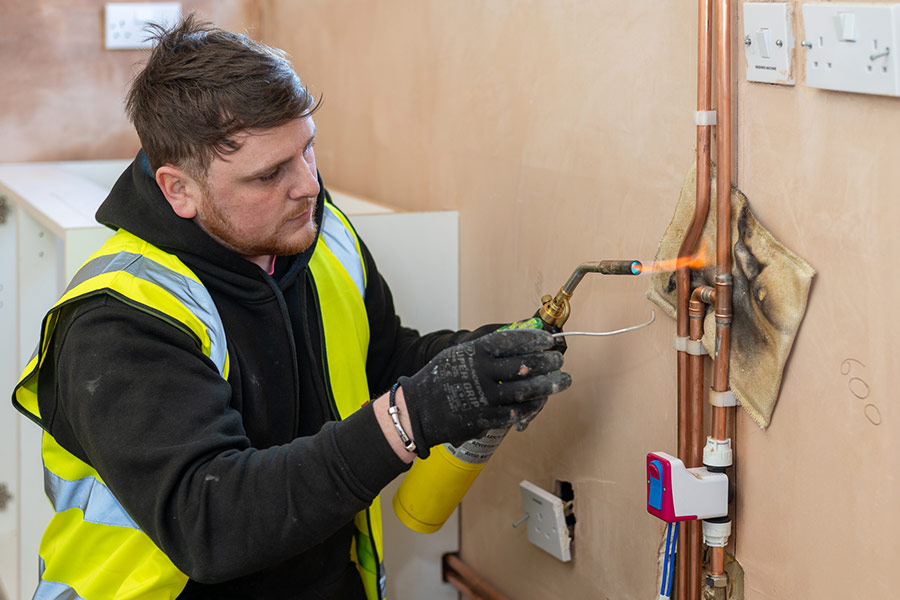 Plumber working on copper pipes with blow torch